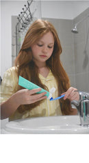 Girl squeezing Flossy & Pure nano-hydroxyapatite toothpaste onto her toothbrush at the bathroom sink