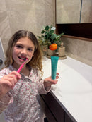 Girl brushing her teeth while holding Flossy & Pure nano-hydroxyapatite toothpaste in her bathroom
